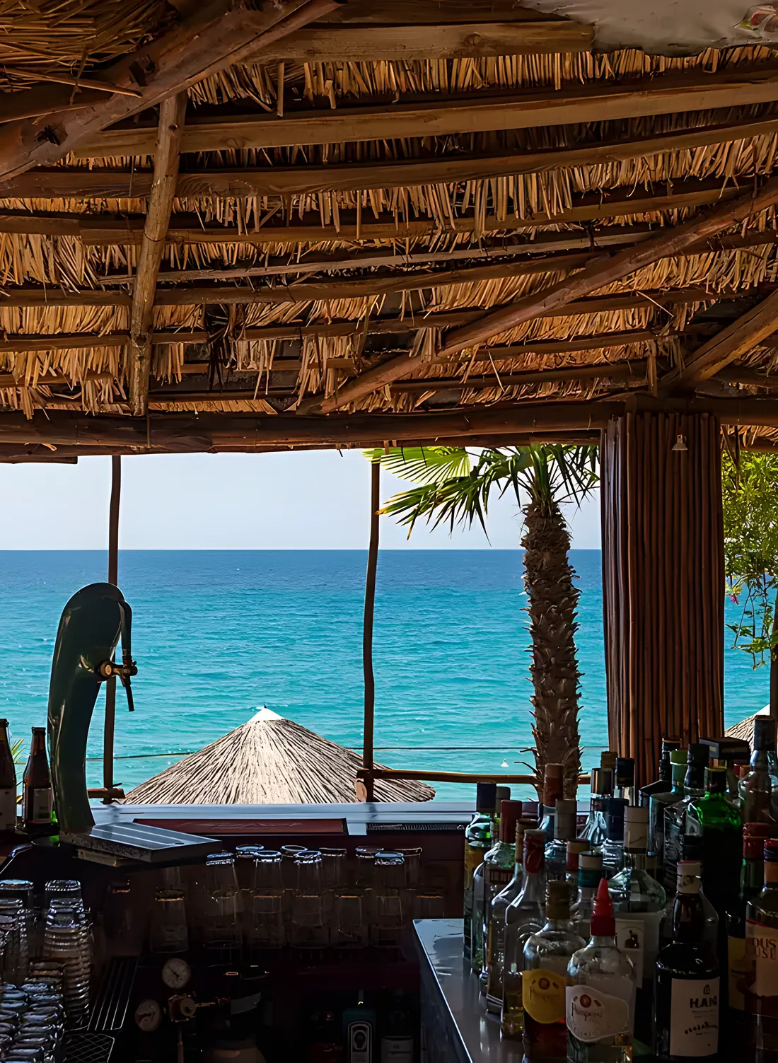Kudu's terrace at golden hour, the low sun turning the sea and umbrellas amber