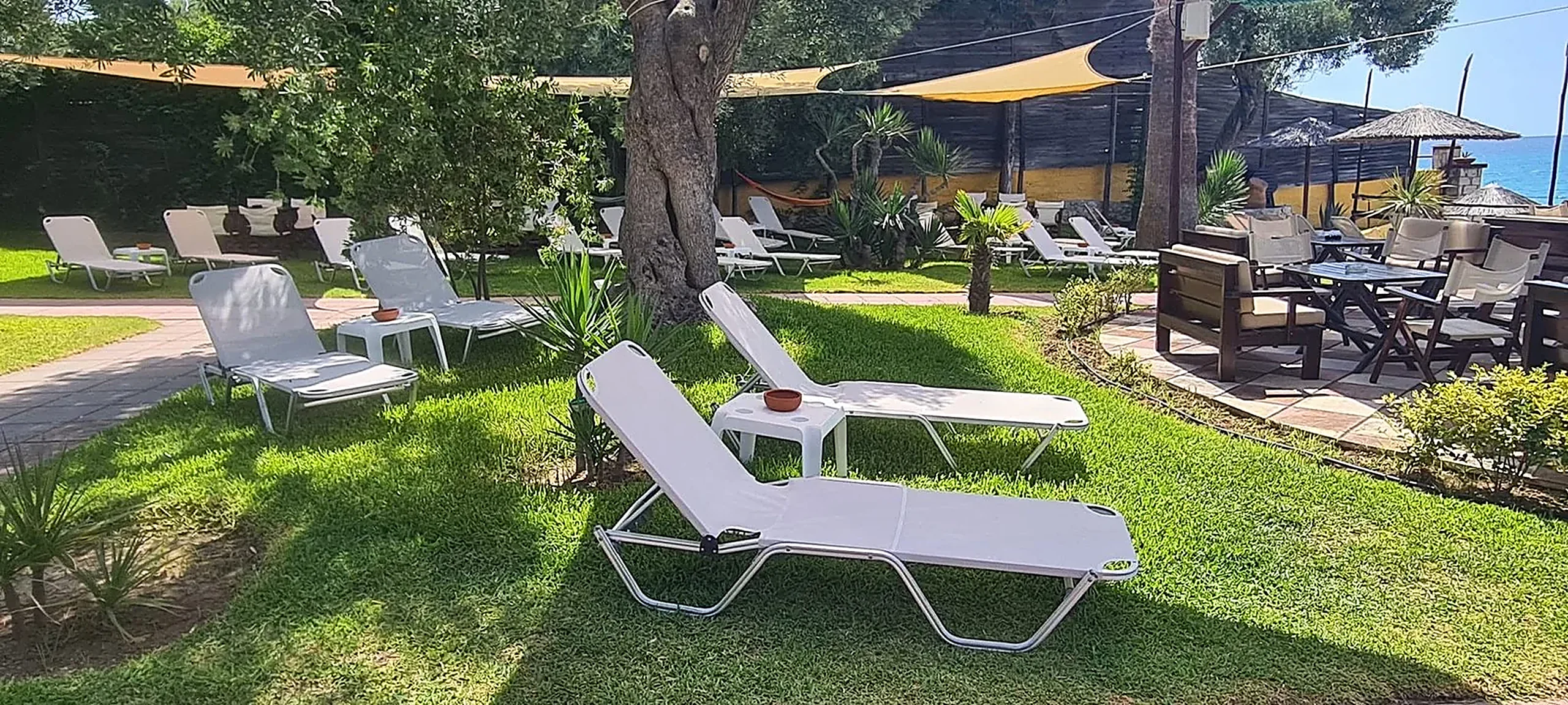 White sunbeds waiting on the lawn at Kudu, the Aegean just beyond